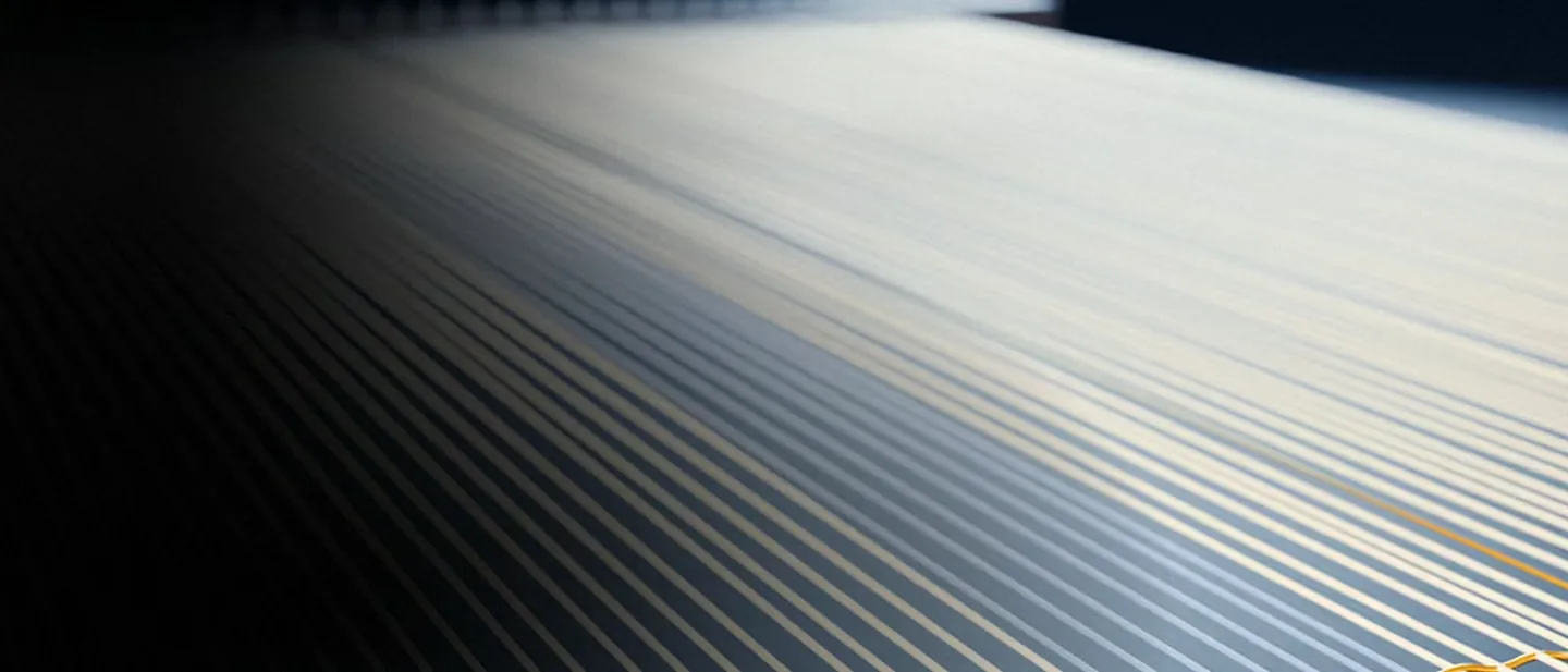 Ivory threads under tension, one gold thread crossing them